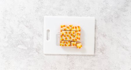 Foto de Piezas cuadradas de caramelo hecho en casa fudge de maíz en una tabla de cortar blanca. - Imagen libre de derechos
