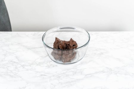 Foto de Mezcla de glaseado de chocolate comprado en una taza de vidrio con una batidora de mano. - Imagen libre de derechos