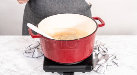Téléchargez les photos : Mélanger les ingrédients dans un four hollandais émaillé pour préparer des pâtes au poulet alfredo. - en image libre de droit