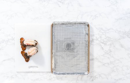 Téléchargez les photos : Pose plate. Queues de homard crues sur une plaque de cuisson avec papier d'aluminium de cuisine, prêtes à être cuites au four. - en image libre de droit