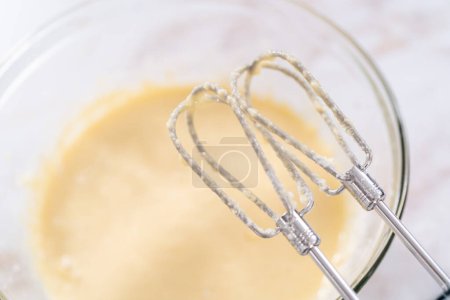 Photo for Mixing ingredients in a large glass mixing bowl to bake apple bundt cake with caramel glaze. - Royalty Free Image