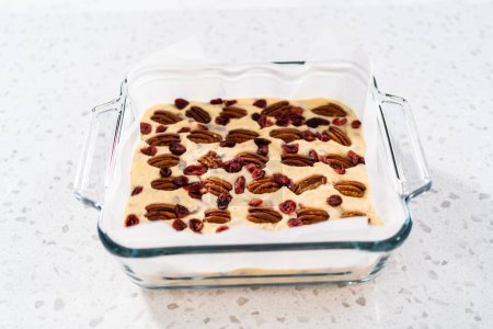 Photo for Removing white chocolate cranberry pecan fudge from the baking pan lined with parchment. - Royalty Free Image