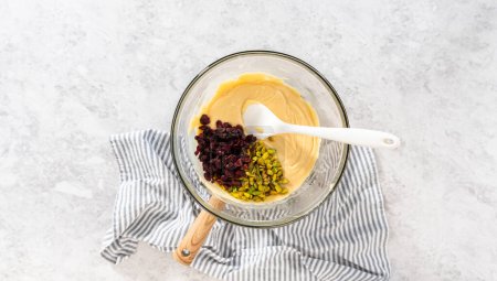 Photo for Flat lay. Melting white chocolate chips and other ingredients in a glass mixing bowl over boiling water to prepare cranberry pistachio fudge. - Royalty Free Image