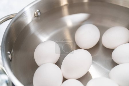 Photo for Boiling white eggs in a cooking pot to prepare hard-boiled eggs. - Royalty Free Image