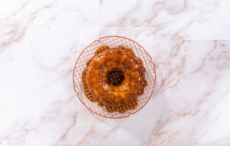 Photo for Flat lay. Pouring homemade caramel glaze over freshly baked apple bundt cake. - Royalty Free Image
