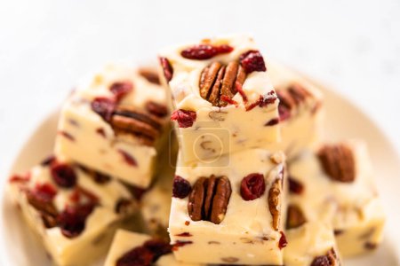 Photo for Homemade white chocolate cranberry pecan fudge pieces on a white ceramic plate. - Royalty Free Image
