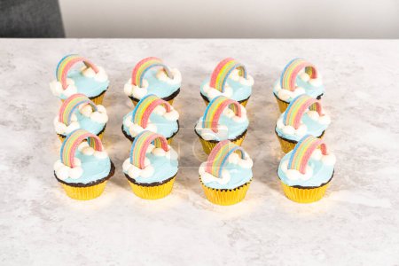 Photo for Chocolate cupcakes decorated with blue buttercream frosting and rainbow for unicorn theme birthday party. - Royalty Free Image
