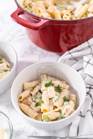 Photo for Chicken alfredo pasta with green peas and rigatoni pasta in a small bowl. - Royalty Free Image
