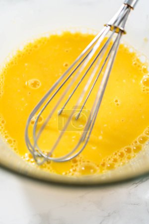 Foto de Galletas de cuña de limón con glaseado de limón. Mezclar ingredientes húmedos en un tazón de vidrio grande para hornear galletas de cuña de limón. - Imagen libre de derechos