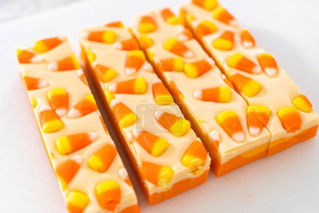Photo for Cutting candy corn fudge into square pieces on a white cutting board. - Royalty Free Image