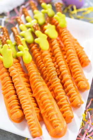 Photo for Carrot chocolate-covered pretzels on a white serving plate for the Easter table. - Royalty Free Image