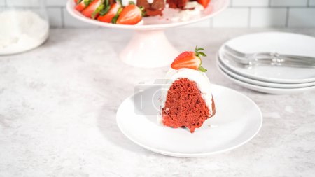 Photo for Step by step. Slice of red velvet bundt cake with cream cheese frosting garnished with fresh strawberries on a white plate. - Royalty Free Image