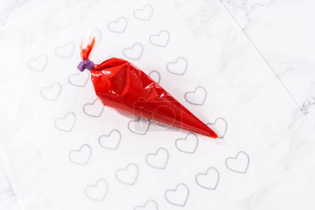 Téléchargez les photos : Piping chocolat fondu de la tuyauterie retour sur le papier parchemin pour faire un cœur de chocolat. - en image libre de droit
