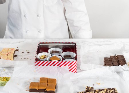 Téléchargez les photos : Emballage d'une variété de caramel maison pour cadeaux alimentaires de Noël dans des boîtes d'étain. - en image libre de droit