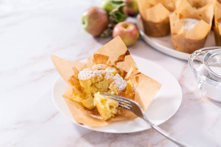 Photo for Eating freshly baked apple sharlotka muffin dusted with powdered sugar. - Royalty Free Image
