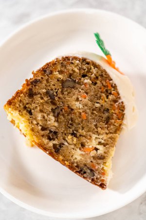 Photo for Slicing freshly baked carrot bundt cake with cream cheese frosting and decorated chocolate carrot cake toppers. - Royalty Free Image