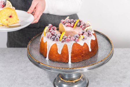 Foto de Tarta de arándanos de limón en rodajas decorada con arándanos de azúcar y cuñas de limón en un puesto de pastel. - Imagen libre de derechos