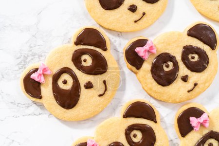 Téléchargez les photos : Biscuits sablés en forme de panda avec glaçage au chocolat sur le comptoir de la cuisine. - en image libre de droit