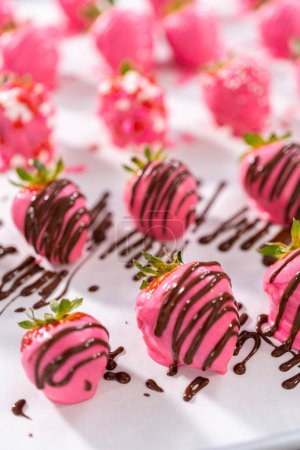 Téléchargez les photos : Décorer les fraises recouvertes de chocolat avec des bruines de chocolat et saupoudrer. - en image libre de droit