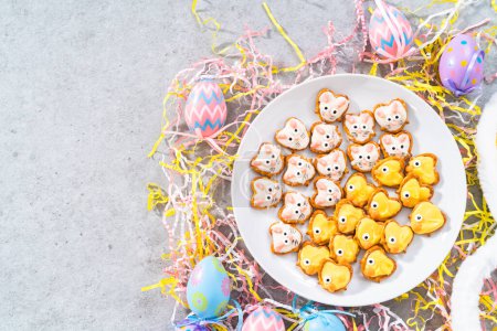 Foto de Conejitos de pretzel cubiertos de chocolate de Pascua y patitos en un plato de servir blanco para la mesa de Pascua. - Imagen libre de derechos