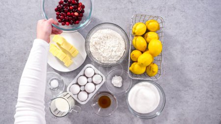 Téléchargez les photos : Pose plate. Pas à pas. Ingrédients dans des bols à mélanger en verre pour préparer le gâteau bundt aux canneberges au citron. - en image libre de droit