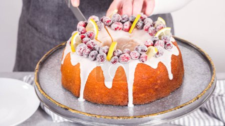 Téléchargez les photos : Pas à pas. Trancher le gâteau de lapin de canneberge au citron décoré de canneberges à sucre et de quartiers de citron. - en image libre de droit