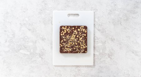 Photo for Flat lay. Scoring chocolate hazelnut fudge using a wheel dough cutter for cutting into small square pieces. - Royalty Free Image