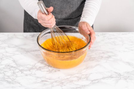 Photo for Mixing ingredients in a large glass mixing bowl to bake chocolate pumpkin bundt cake with toffee glaze. - Royalty Free Image