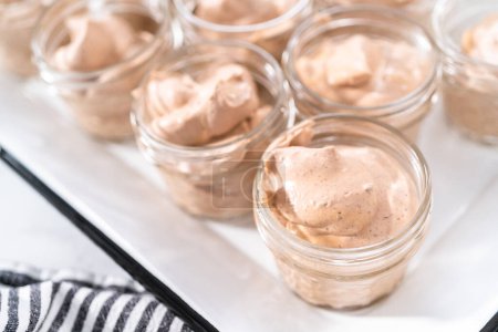 Téléchargez les photos : Mélange à ramasser dans les petits pots en verre pour faire de la crème glacée au chocolat maison. - en image libre de droit