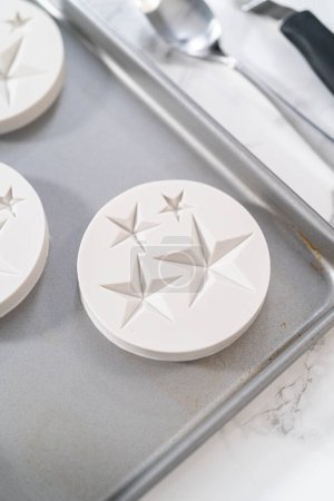 Foto de Filling silicone mold with white melted chocolate to make chocolate chocolate stars for American flag mini cupcakes. - Imagen libre de derechos