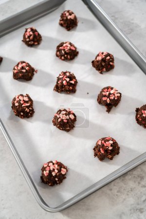 Photo for Scooping chocolate cookie dough with dough scoop to bake chocolate cookies with peppermint chips. - Royalty Free Image
