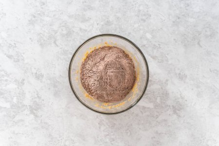 Téléchargez les photos : Pose plate. Mélanger les ingrédients dans un grand bol de mélange en verre avec un mélangeur de cuisine pour cuire des biscuits au chocolat avec des copeaux de menthe poivrée. - en image libre de droit
