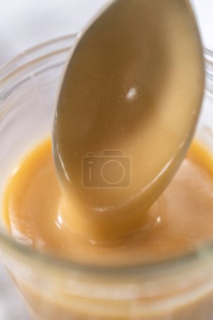 Photo for Homemade toffee glaze in a glass jar on the kitchen counter. - Royalty Free Image