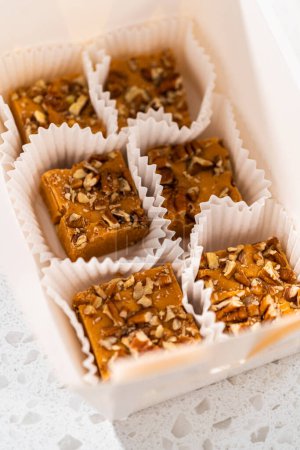 Foto de Embalaje de caramelo de especias de calabaza casera con pacanas en una caja de regalo de papel blanco. - Imagen libre de derechos