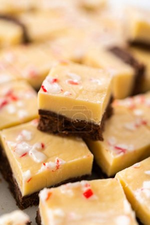 Téléchargez les photos : Couper le caramel à la canne à sucre avec un grand couteau de cuisine en morceaux carrés sur une planche à découper blanche. - en image libre de droit