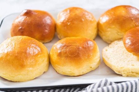 Freshly baked brioche buns on a metal serving tray.