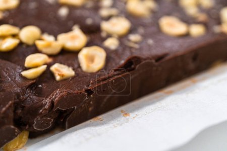 Foto de Extracción de caramelo de avellana de chocolate de una sartén cuadrada de pastel de queso forrada con pergamino. - Imagen libre de derechos