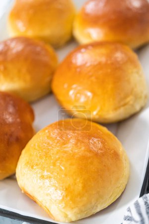 Freshly baked brioche buns on a metal serving tray.