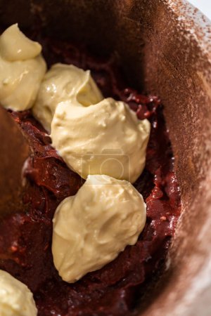 Foto de Llenado de pan de pastel de metal con mantequilla de pastel para hornear pastel de terciopelo rojo con glaseado de queso crema - Imagen libre de derechos