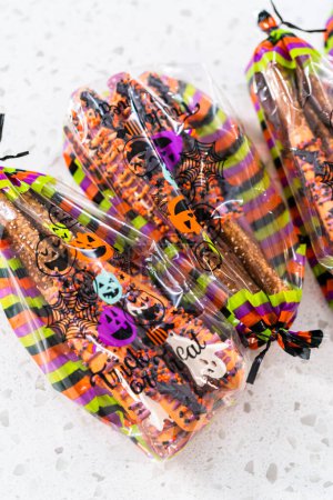 Foto de Embalaje Halloween barras de pretzel cubiertas de chocolate con aspersiones en bolsas de regalo. - Imagen libre de derechos