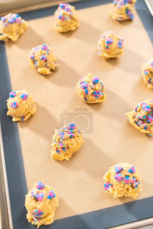 Foto de Bolitas de masa de galletas refrigeradas en la bandeja para hornear galletas de chispas de chocolate unicornio. - Imagen libre de derechos