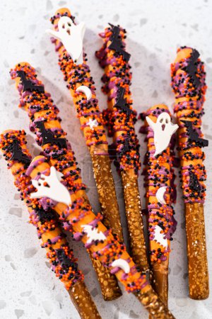 Téléchargez les photos : Pose plate. Baguettes de bretzel recouvertes de chocolat Halloween avec saupoudrer sur un comptoir de cuisine. - en image libre de droit