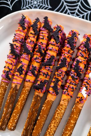 Foto de Barras de pretzel cubiertas de chocolate de Halloween con salpicaduras en un plato de servir blanco. - Imagen libre de derechos