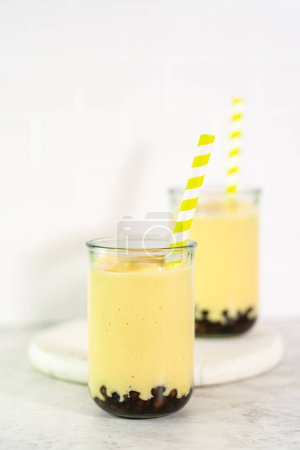 Téléchargez les photos : Smoothie de mangue boba fraîchement préparé dans un verre à boire avec une paille de papier. - en image libre de droit