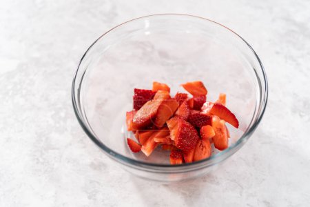 Téléchargez les photos : Découpe de fraises fraîches sur une planche à découper blanche pour préparer le glaçage à la crème au beurre aux fraises. - en image libre de droit