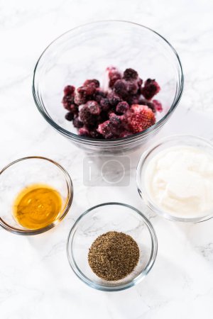 Photo for Measured ingredients in glass mixing bowls to prepare mixed berry smoothie. - Royalty Free Image