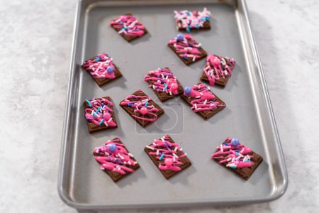 Téléchargez les photos : Mini chocolats noirs gourmands avec chocolat rose arrosé et saupoudrées fantaisie sur le dessus. - en image libre de droit