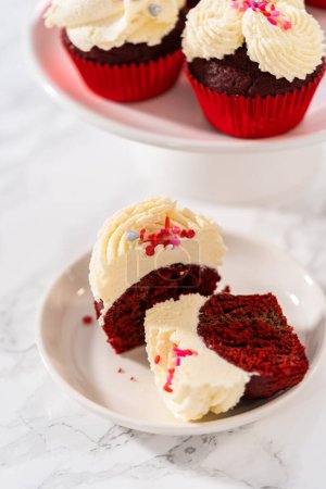 Foto de Cupcakes de terciopelo rojo en rodajas con glaseado de ganache de chocolate blanco en un plato blanco. - Imagen libre de derechos