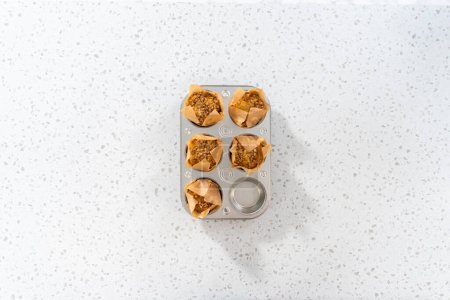 Photo for Flat lat. Freshly baked banana oatmeal muffins in small muffin pan. - Royalty Free Image