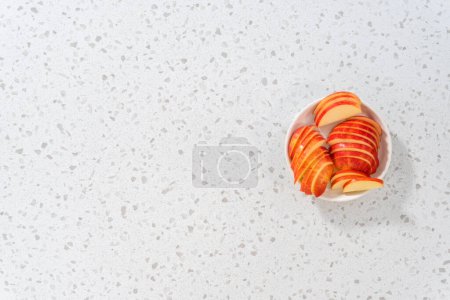 Foto de Acostado. Manzanas rojas en rodajas finas en un plato blanco. - Imagen libre de derechos